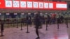 Geneva, Switzerland - People wearing protective masks walk in the departure terminal of Cointrin airport, the day the Swiss government imposed a 10 days quarantine for travellers who have entered from Britain, during the outbreak of the coronavirus diseas