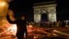 FRANCE -- A yellow vest (Gilets jaunes) protestor gestures as others add to burning material near The Arc de Triomphe on the Champs Elysees in Paris, on November 24, 2018, during a rally against rising oil prices and living costs. - Security forces in Par